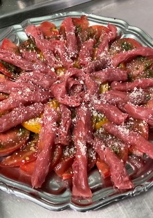 A picture of Beef Carpaccio with Heirloom Tomatoes and Parmesan.