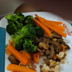 A picture of Steamed carrots broccoli over baked chicken in mushroom sauce.