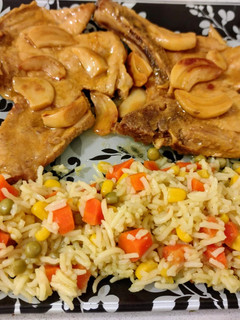 Una foto de Chuletas de cerdo al ajillo con naranja y arroz tres delicias