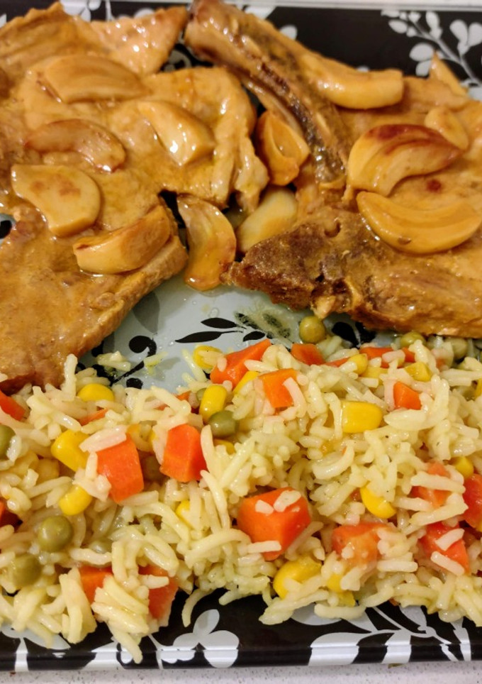 Una foto de Chuletas de cerdo al ajillo con naranja y arroz tres delicias