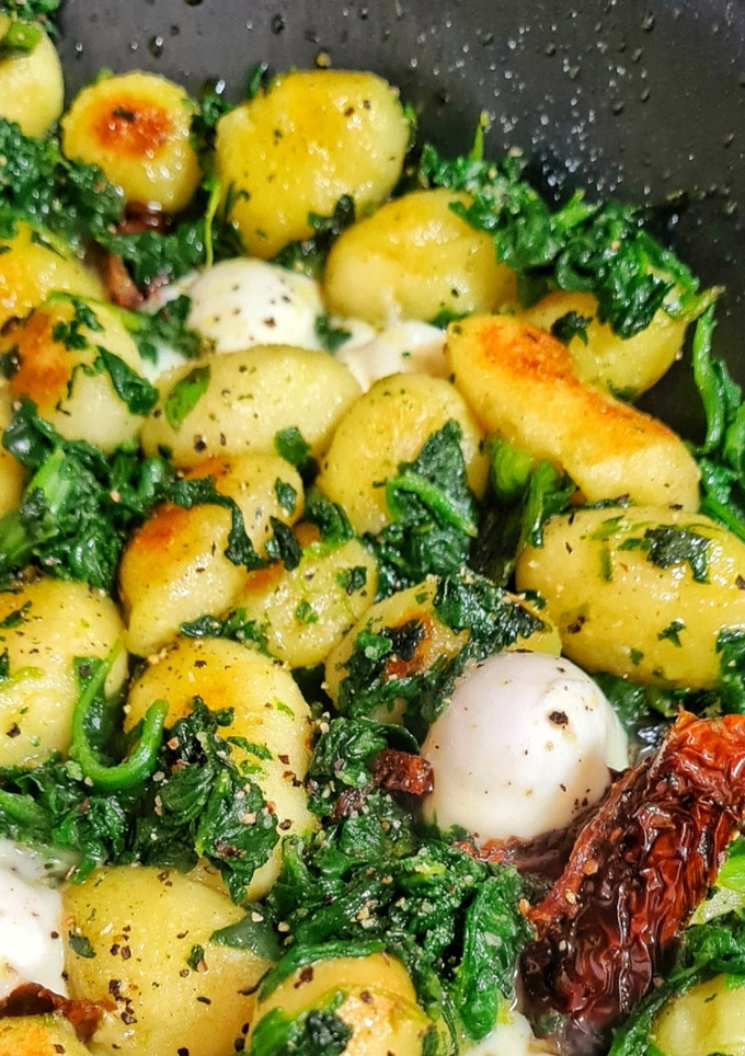 Una foto de Ñoquis salteados con tomates secos, espinacas y queso mozzarella