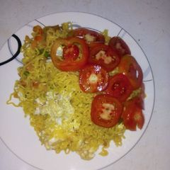 A picture of Jollof indomie and egg with sliced tomatoes.