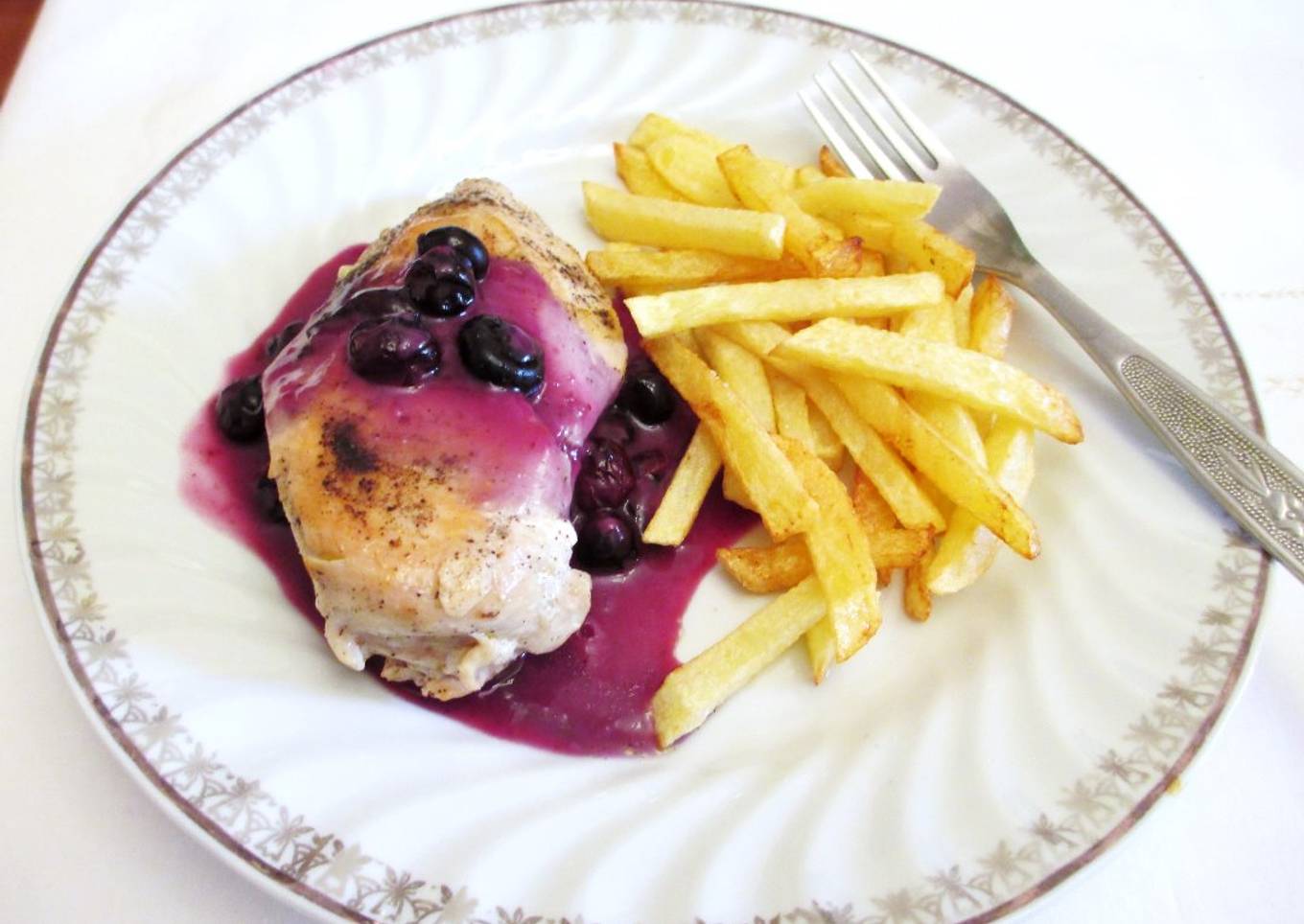 Pechuga de pollo bañada con salsa de arándanos y patatas pajas