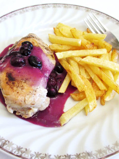 Una foto de Pechuga de pollo bañada con salsa de arándanos y patatas pajas