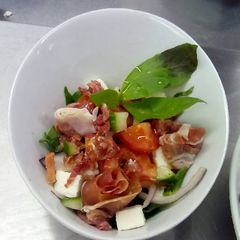 A picture of Greek salad, with cured meats and vinaigrette.