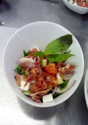 A picture of Greek salad, with cured meats and vinaigrette.