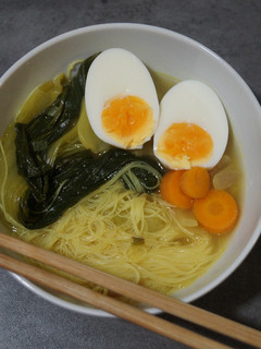 Una foto de Ramen con caldo de pollo, fideos de arroz y pak choi