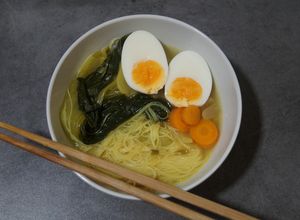 Una foto de Ramen con caldo de pollo, fideos de arroz y pak choi