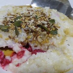 A picture of Brown rice porridge with frozen raspberries.