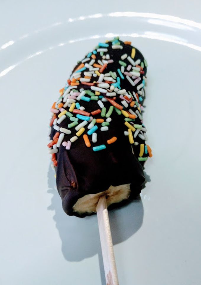 Una foto de Plátanos helados con cobertura de chocolate y virutas de colores