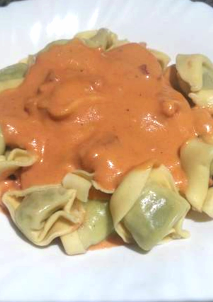 Una foto de Tortellinis rellenos con salsa de tomate, nata y bacon
