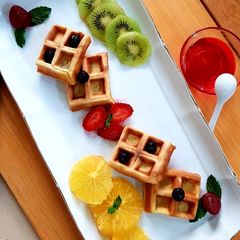 A picture of Waffles with fresh fruits & strawberry syrup.