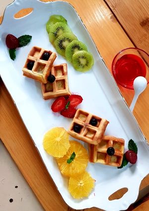 A picture of Waffles with fresh fruits & strawberry syrup.