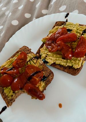 A picture of Avocado toast with fried tomatoes.