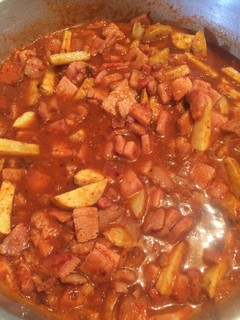 A picture of Chuleta ahumada con papas en salsa roja.