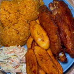 A picture of Jollof rice and turkey with coselaw and fried plantain.