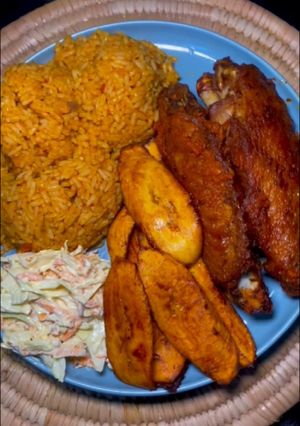 A picture of Jollof rice and turkey with coselaw and fried plantain.