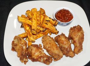 Una foto de Alas de pollo adobadas y bastones de camote amarillo asado