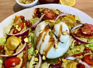 Une photo de Salade de patate douce rôtie, guacamole, Shakshuka Omie, oignons rouges, burrata et pistaches