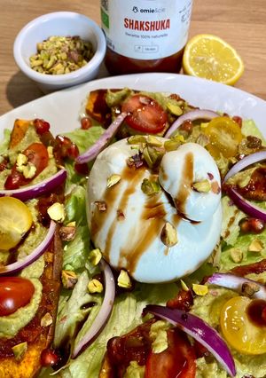 Une photo de Salade de patate douce rôtie, guacamole, Shakshuka Omie, oignons rouges, burrata et pistaches
