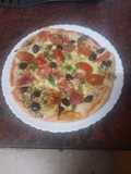 Pizza de rúcula, jamón serrano, aceitunas negras y tomates cherry macerados