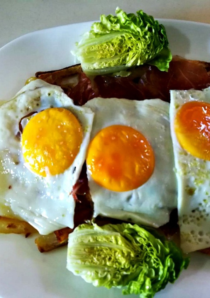 Una foto de Patatas fritas en el horno con jamón y huevos