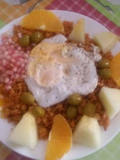 Una foto de Migas con chorizos, melón, naranja, granadas, huevo y aceitunas