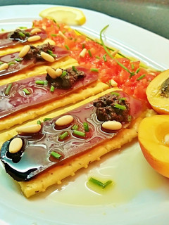 Una foto de Pincho de mojama con olivada, tomate, albaricoque y piñones