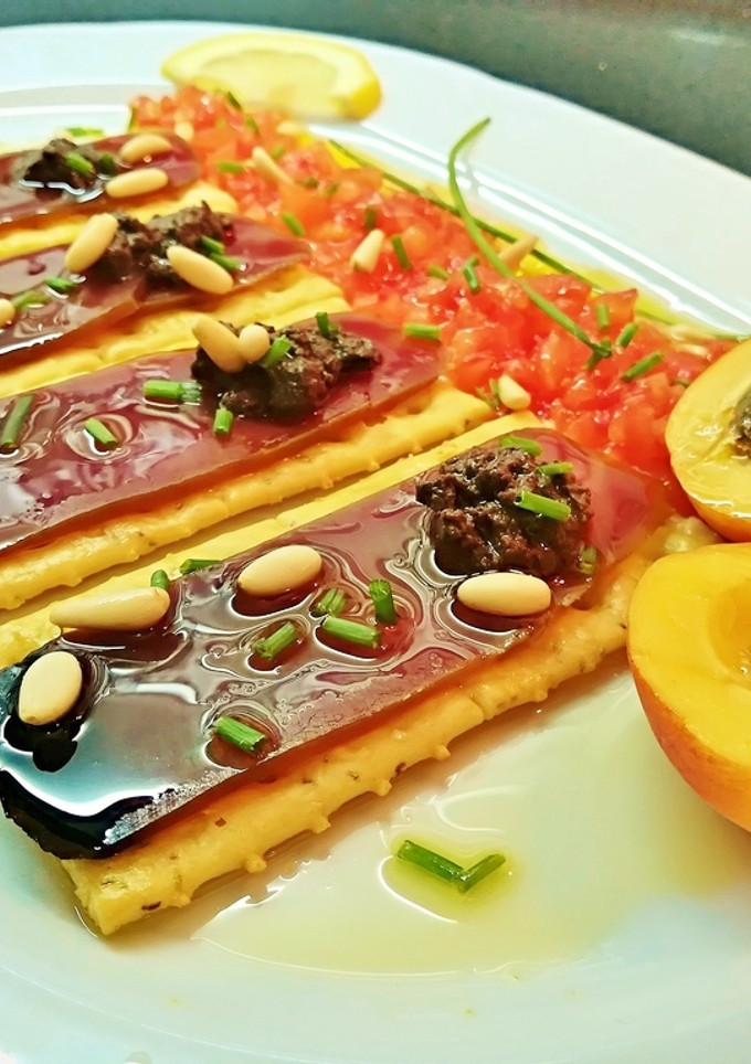Una foto de Pincho de mojama con olivada, tomate, albaricoque y piñones