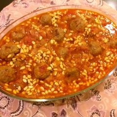A picture of Meatballs and pine nuts in tomato sauce.