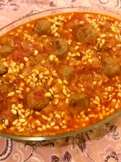 A picture of Meatballs and pine nuts in tomato sauce.