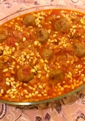 A picture of Meatballs and pine nuts in tomato sauce.