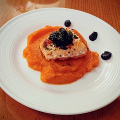A picture of Sauteed salmon filet on sweet potato puree with bluberry compote.