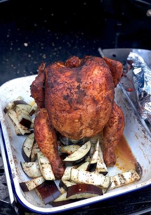 A picture of Beer can chicken on the Braai (BBQ) with coal charred corn on the cob.