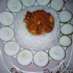 A picture of White rice and water snail stew, garnished with cucumber.