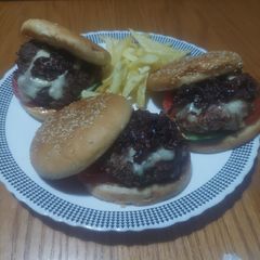 A picture of Beef-lamb burger with caramelized onions,cheese, tomato&cucumber.