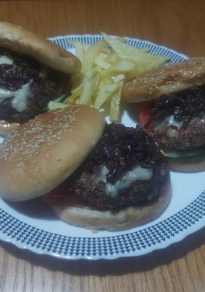 A picture of Beef-lamb burger with caramelized onions,cheese, tomato&cucumber.