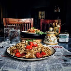 A picture of Basil pesto spaghetti with loads of cherry tomatoes.