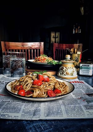 A picture of Basil pesto spaghetti with loads of cherry tomatoes.