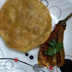 A picture of Kashmiri Khatte Baigan with Khasta Puri.