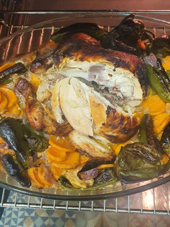 Una foto de Pollo al horno sobre leche evaporada, boniato, cebolla y padrones