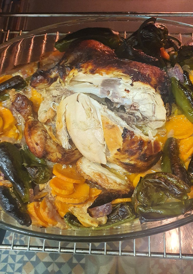 Una foto de Pollo al horno sobre leche evaporada, boniato, cebolla y padrones