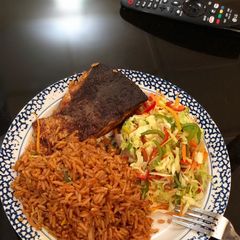 A picture of Jollof rice, fresh veggie salad with Salmon.
