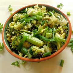 A picture of Fried rice topped with green veggies.