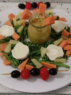 Una foto de Ensalada de rúcula con guacamole, frutas y queso de cabra