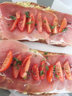 Una foto de Brusquetta de guacamole, jamón chudo y tomates cherry