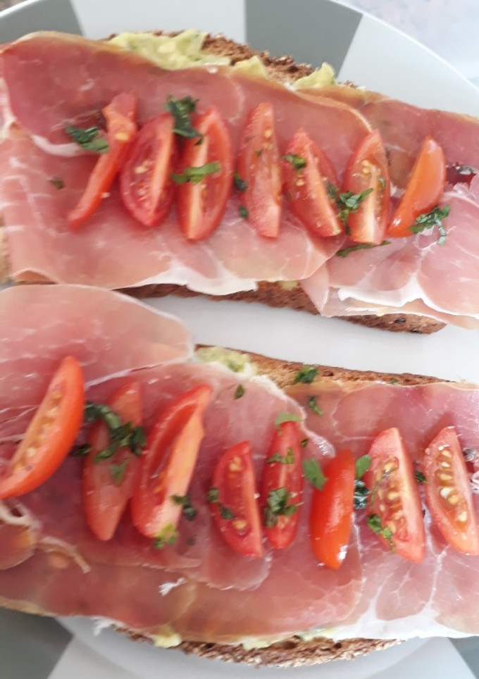 Una foto de Brusquetta de guacamole, jamón chudo y tomates cherry