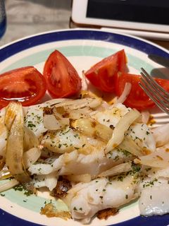 Una foto de Merluza con cebolla, perejil y tomate