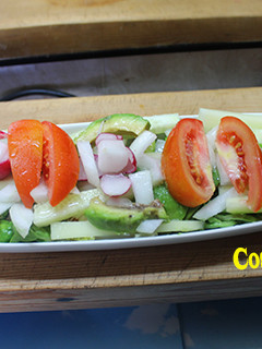 Una foto de Ensalada de aguacate, pepino, tomate y flores de rábano
