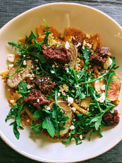 A picture of Farfalle with tomato pesto cream, beets, aragula, beyond meat.